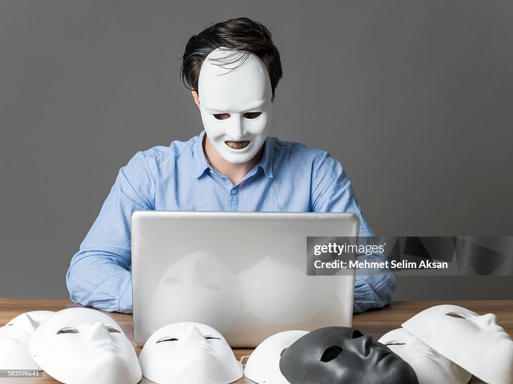 Computer hacker wearing a mask using computer