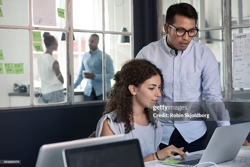 Man and Woman looking at laptop in office