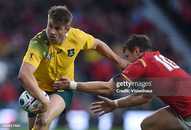 Drew Mitchell of Australia offloads the ball before he is tackled by Dan Biggar and Liam Williams of Wales during the Rugby World Cup 2015 Group A...