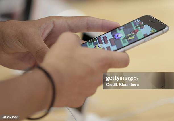 Customer tries out an Apple Inc. IPhone 6s Plus inside a SoftBank Group Corp. Store in Tokyo, Japan, on Tuesday, July 26, 2016. SoftBank rose in...