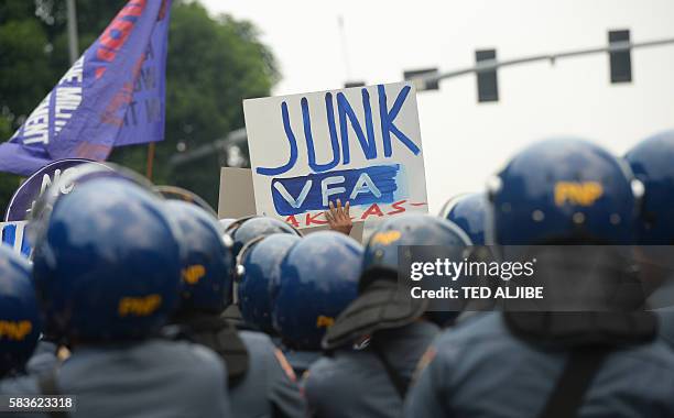 An activist displays an anti-US placard in front of police during a protest at the US embassy to coincide with US Secretary of State John Kerry's...