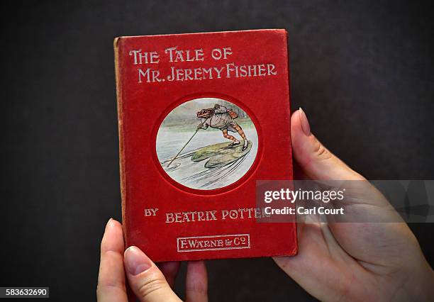 An assistant holds a first edition of The Tale of Mr Jeremy Fisher by Beatrix Potter at Dreweatts and Bloomsbury Auctions on July 27, 2016 in London,...