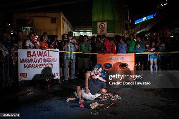 Woman clutches her dead husband in grief after armed assailants in a motorcycle shot him in a main thoroughfare on July 23, 2016 in Manila,...