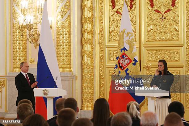 Russian pole vaulter Yelena Isinbayeva speaks as Russian President Vladimir Putin looks on during a meeting with the Russian national Olympic team,...