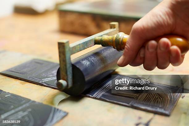 printmaker inking lino print block - lino stockfoto's en -beelden