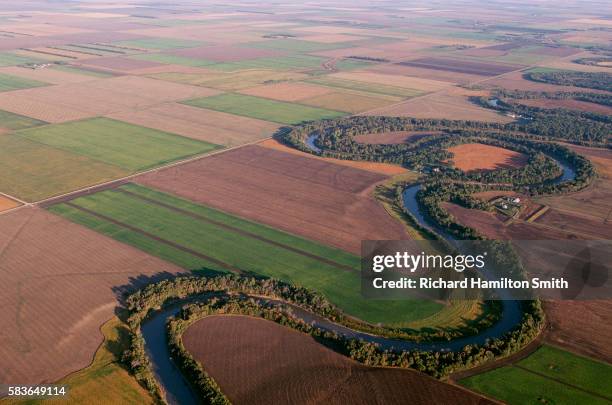red river winds through fields - terra coltivata foto e immagini stock
