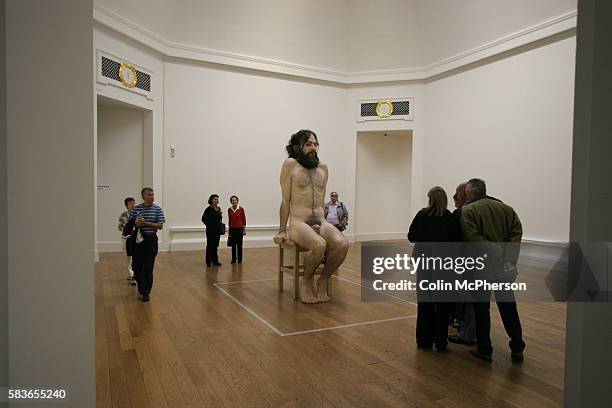 Visitors to Ron Mueck's latest exhibition look at the waxwork human figure entitled A Girl, 2006 on display at the Royal Scottish Academy. The show...