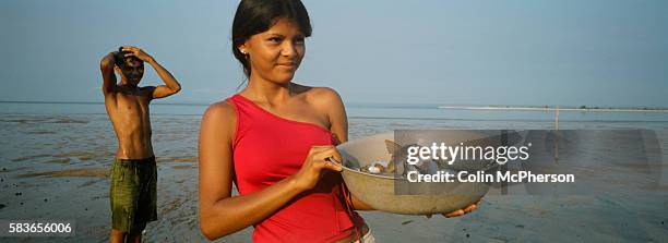 Young girl holds up a bowl of freshly caught fish from the Tapajos river in the Amazonian basin. Villagers along the freshwater river lived from...