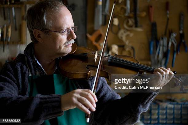 Andrew Hutchinson testing a violin and bow which he has just completed repairing and restoring at his workshop at Hoylake, Wirral, north west...