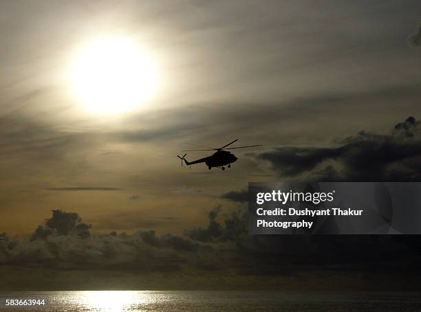 silhouette of helicopter over the ocean - military helicopter fotografías e imágenes de stock