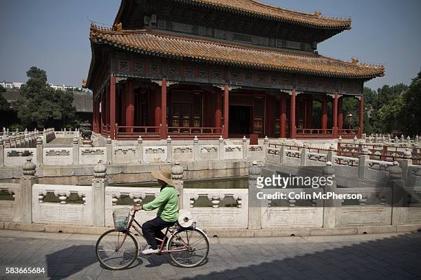 Woman on a bicycle cycling past one of the temples at the Confucius Temple and Guozijian in Beijing, China. The complex was first built during the...
