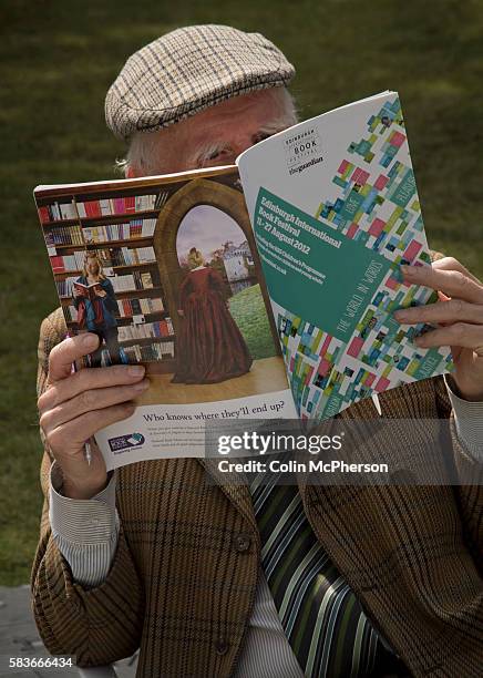 An elderly man wearing traditional Tweed jacket and cap reading the official programme on the opening weekend of the the Edinburgh International Book...