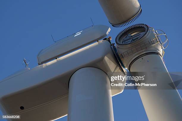 Engineers wait as one of the last remaining 11-ton blades on a 2.5 megawatt wind turbine at Alexandra Dock in Liverpool is lifted into place by...