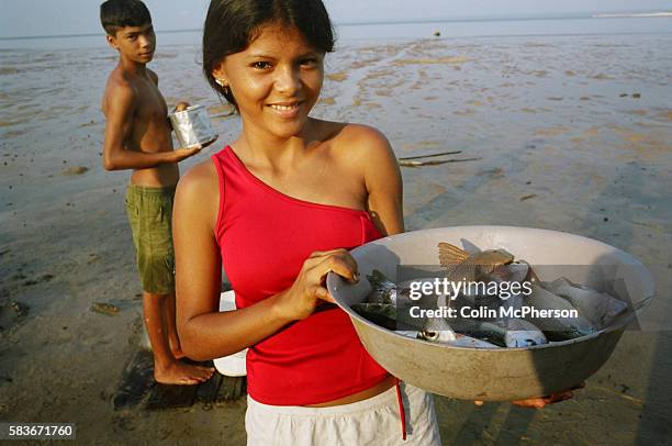 Young girl holds up a bowl of freshly caught fish from the Tapajos river in the Amazonian basin. Villagers along the freshwater river lived from...