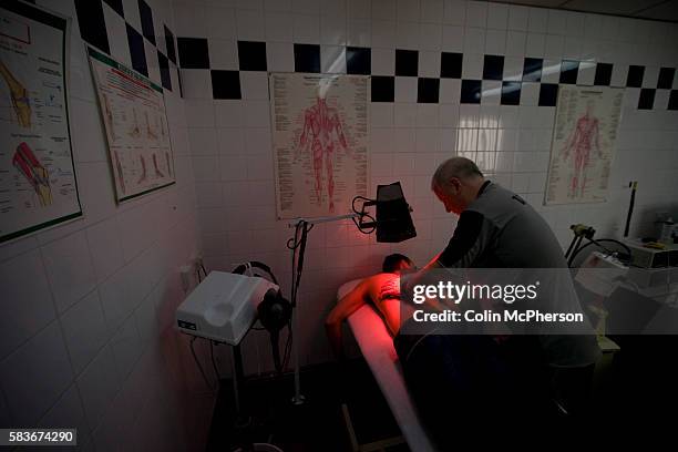 Tranmere Rovers' club physio Les Parry in the club's treatment room using an infra-red lamp to treat one of the club's youth team players for a back...