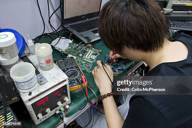 An electronics engineer repairing a laptop computers at a retail unit housed within the Zhongguancun e-plaza, Beijing, China which sells...