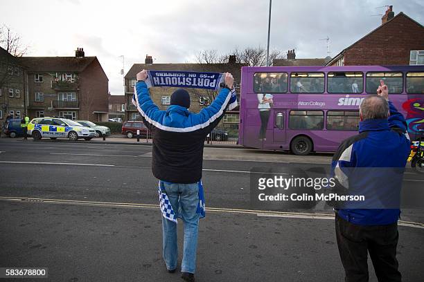 Portsmouth fans waving and gesturing to rival Southampton fans in a convoy of buses driving away from Fratton Park stadium after the teams...