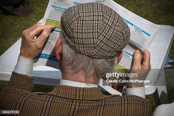 An elderly man wearing traditional Tweed jacket and cap reading the official programme on the opening weekend of the the Edinburgh International Book...