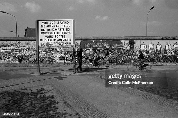 Sign indicating the end of the American sector next to the Berlin Wall at Potsdamer Platz, West Berlin. The Berlin Wall was a barrier constructed by...