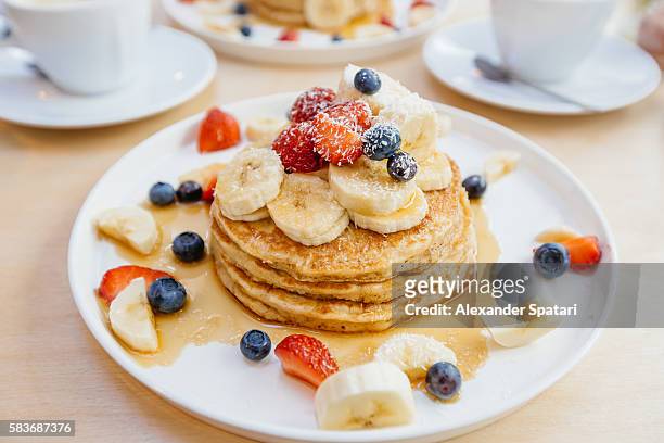 stack of pancakes with maple syrup, banana, strawberry and blueberry on the plate - dessert bildbanksfoton och bilder