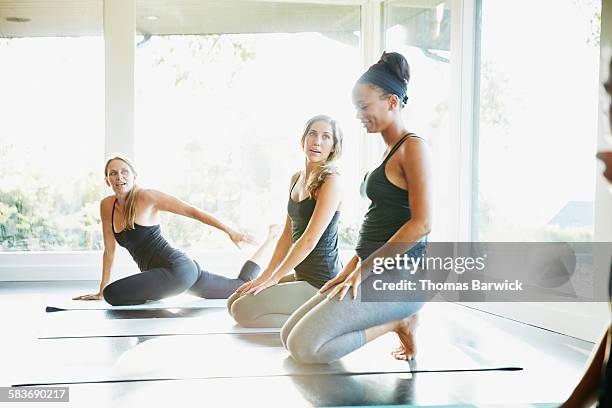 Smiling female yoga instructor kneeling on mat