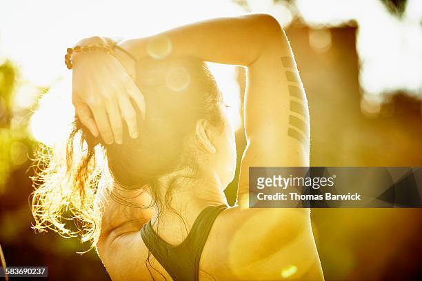 Woman with arms raised overhead looking at sunset