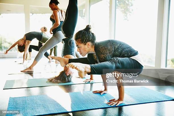 woman practicing yoga in crow pose during class - control pants foto e immagini stock