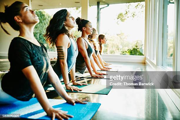 Women practicing yoga in studio in cobra pose