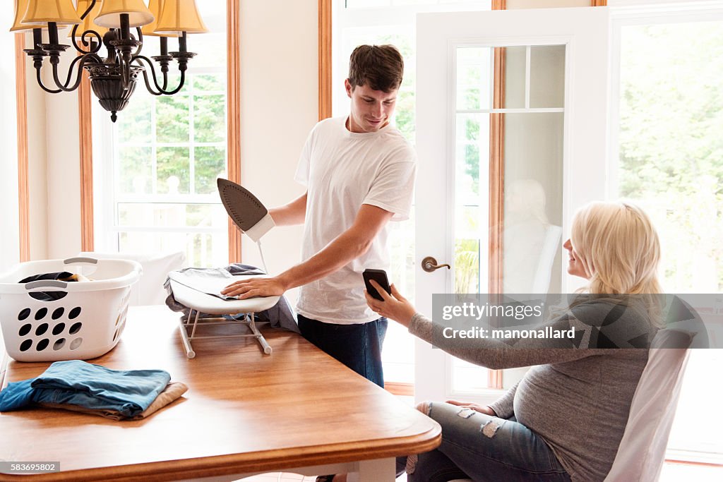 Pregnant woman shows a men ironing something on his cell