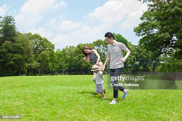 公園で手をつないで走っている家族 - 家族　日本人　走る ストックフォトと画像