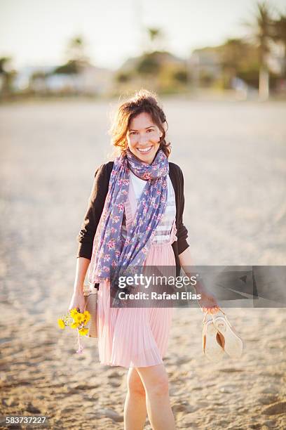 woman on the beach holding flowers and shoes - großes halstuch stock-fotos und bilder