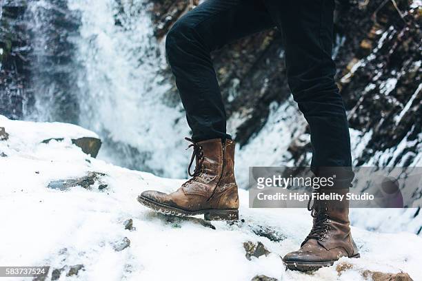legs in boots on the background of waterfall in winter - calzature di pelle foto e immagini stock