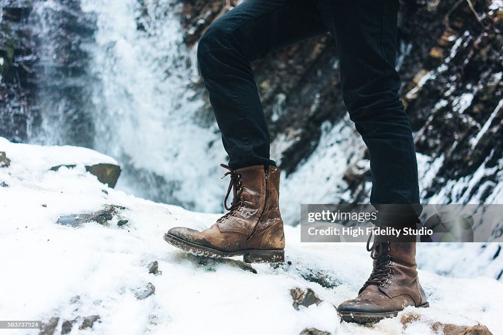 Legs in boots on the background of waterfall in winter