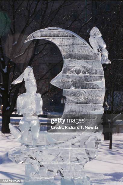 ice sculpture of man sitting on crescent moon - ice sculpture stock-fotos und bilder