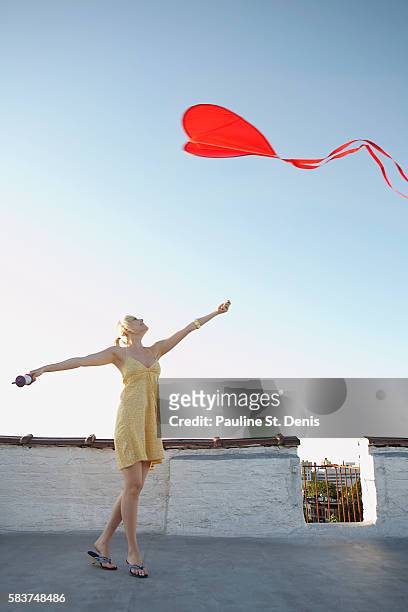 woman flying heart-shaped red kite - kite toy foto e immagini stock