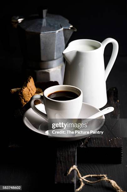 cup of hot espresso, creamer with milk, cantucci and moka coffee pot on a rustic wooden board - moka pot stockfoto's en -beelden