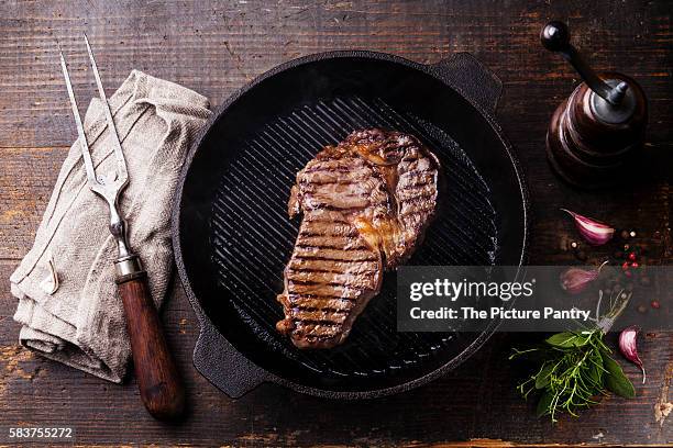 grilled ribeye steak entrecote on grill pan on wooden background - entrecôte stockfoto's en -beelden