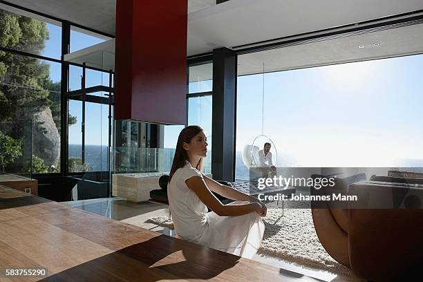 man and woman sitting far apart - femme salon photos et images de collection