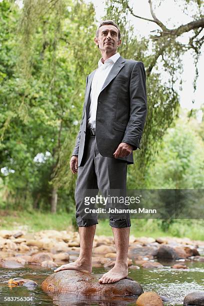 businessman standing on rock in stream - bare feet male tree stock pictures, royalty-free photos & images