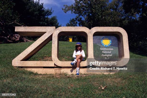 girl sitting on national zoo sign - smithsonian national zoological park stock pictures, royalty-free photos & images