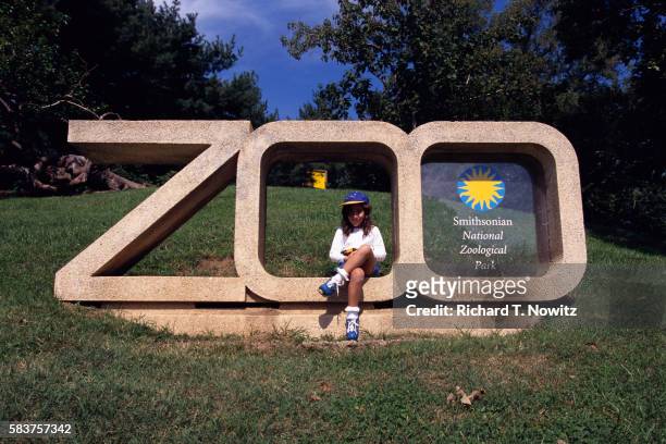 girl sitting on national zoo sign - jardim zoológico de washington imagens e fotografias de stock
