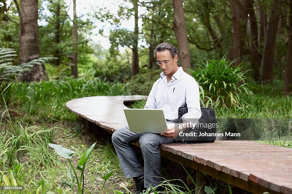 Man Sitting on Walkway Using Laptop Computer