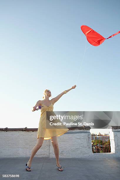 woman flying red kite on rooftop - kite toy foto e immagini stock
