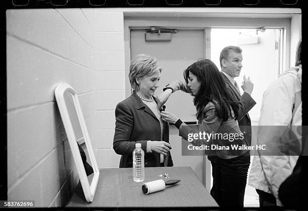 Presidential candidate Senator Hillary Rodham Clinton has a microphone attached to her lapel by her personal assistant, Huma Abedin, while waiting...