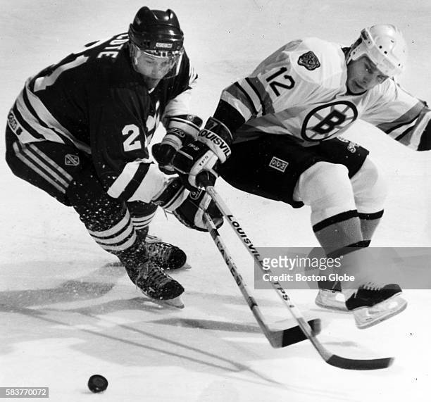 Boston Bruins player Randy Burridge, right, and Hartford Whalers player Sylvain Cote, left, go for a loose puck, during a game at the Boston Garden...
