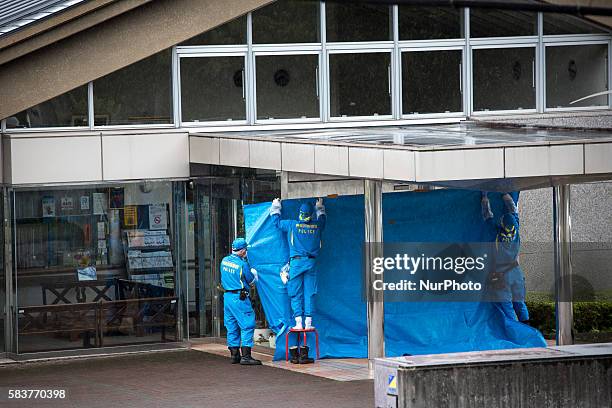 Police investigators try to cover the main entrance of Tsukui Yamayuri-en building as they continue to investigate on knife attack in a handicap...
