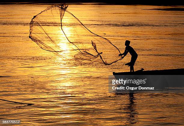 fisherman casting net on river, varanasi, india - pescador - fotografias e filmes do acervo