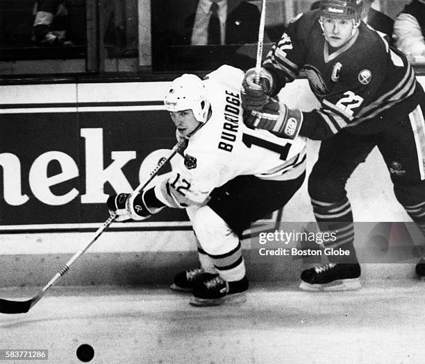 Boston Bruins player Randy Burridge, left, and Buffalo Sabres player Lindy Ruff go for a loose puck during a game at Boston Garden in Boston on Dec....