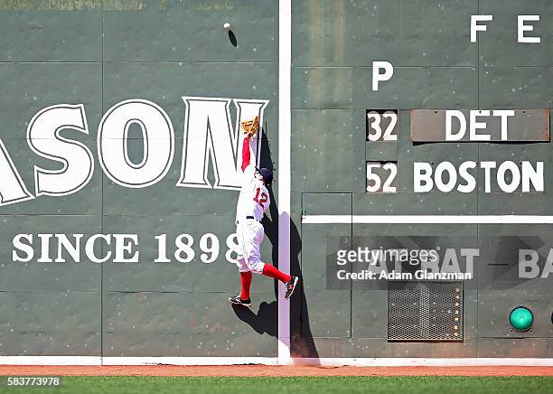 Brock Holt of the Boston Red Sox reaches for a ball that bounces of the Green Monster in the third inning during the game against the Detroit Tigers...