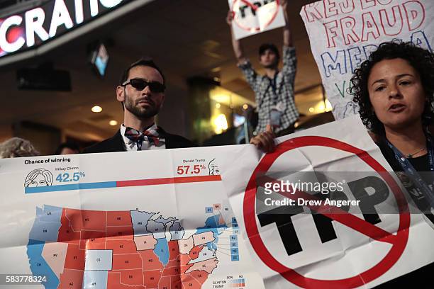 Attendees hold up signs that read 'Trans-Pacific Partnership ' and a presidential election forecast map on the third day of the Democratic National...